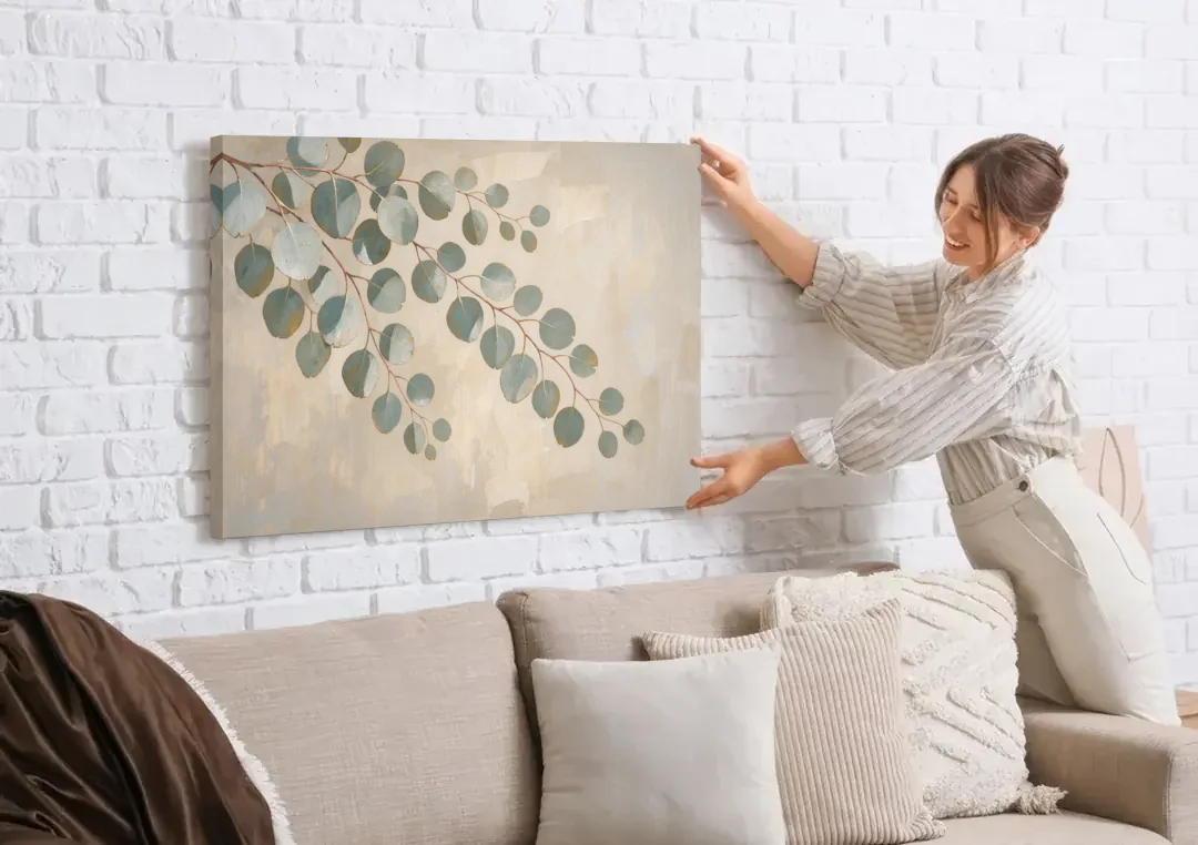Greenery Wall Art of Trailing Silver Dollar Eucalyptus canvas wall art being hung on a white brick wall above a sofa