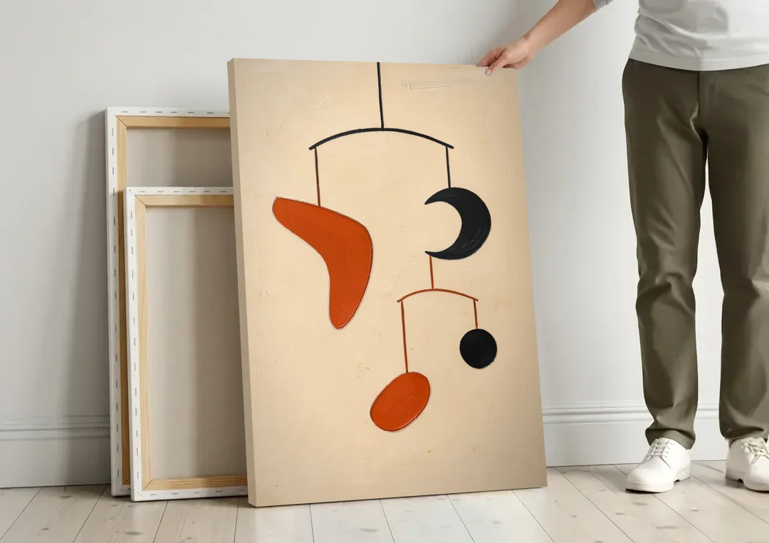 Hanging Mobile of Vermilion and Black Shapes canvas wall art leaning against a wall next to blank canvases