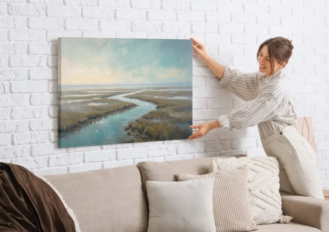 Horizon Wall Art of a Lowcountry Marsh at Dawn canvas wall art being hung on a white brick wall above a sofa