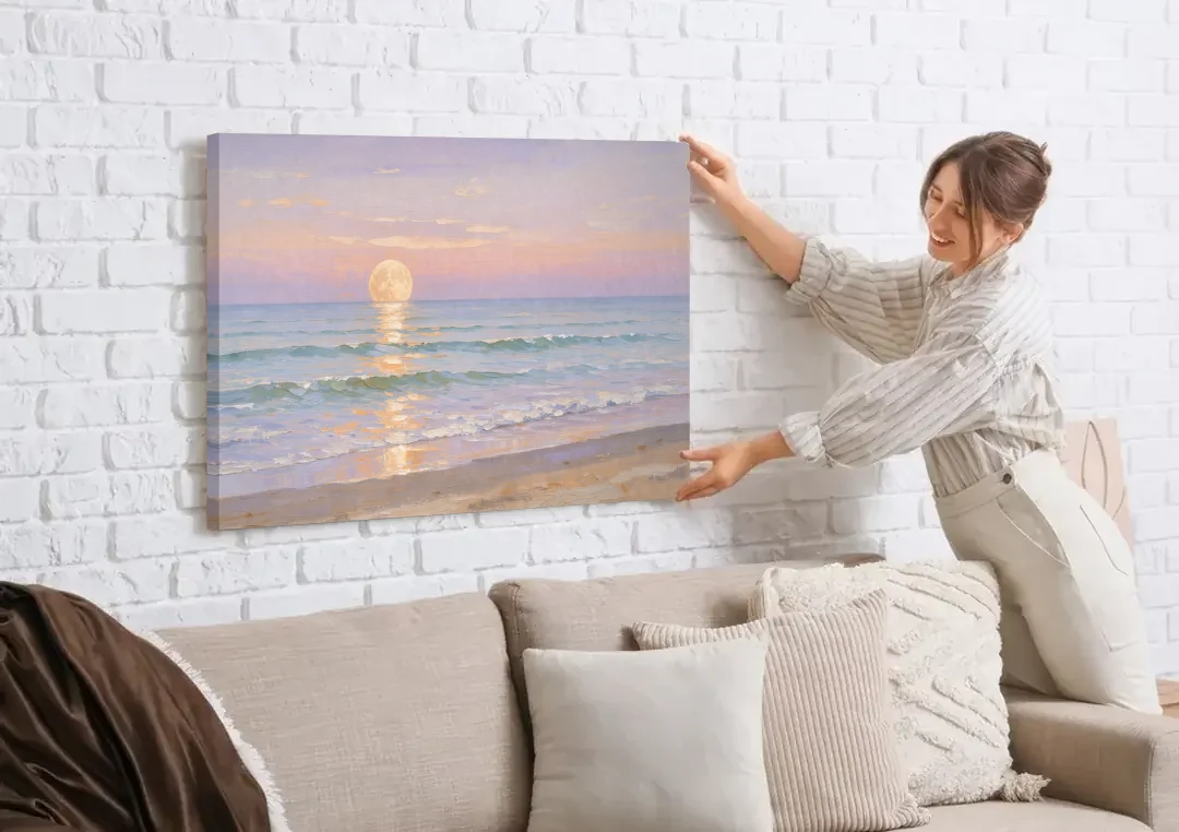 Large Golden Moonrise Over Rolling Ocean Surf canvas wall art being hung on a white brick wall above a sofa
