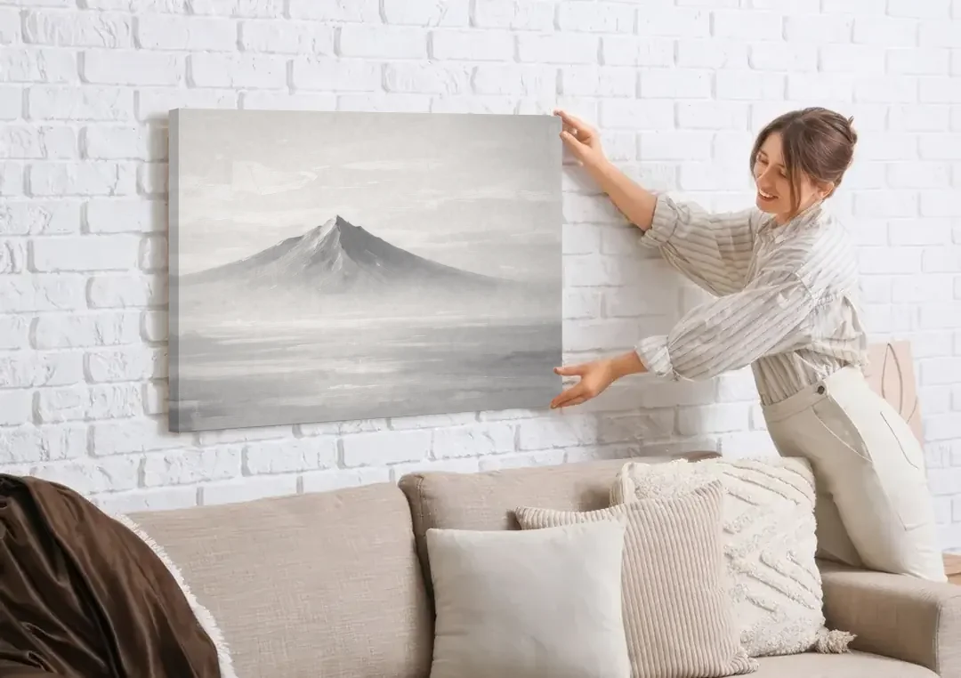 Lone Mountain Peak Above a Sea of Mist canvas wall art being hung on a white brick wall above a sofa