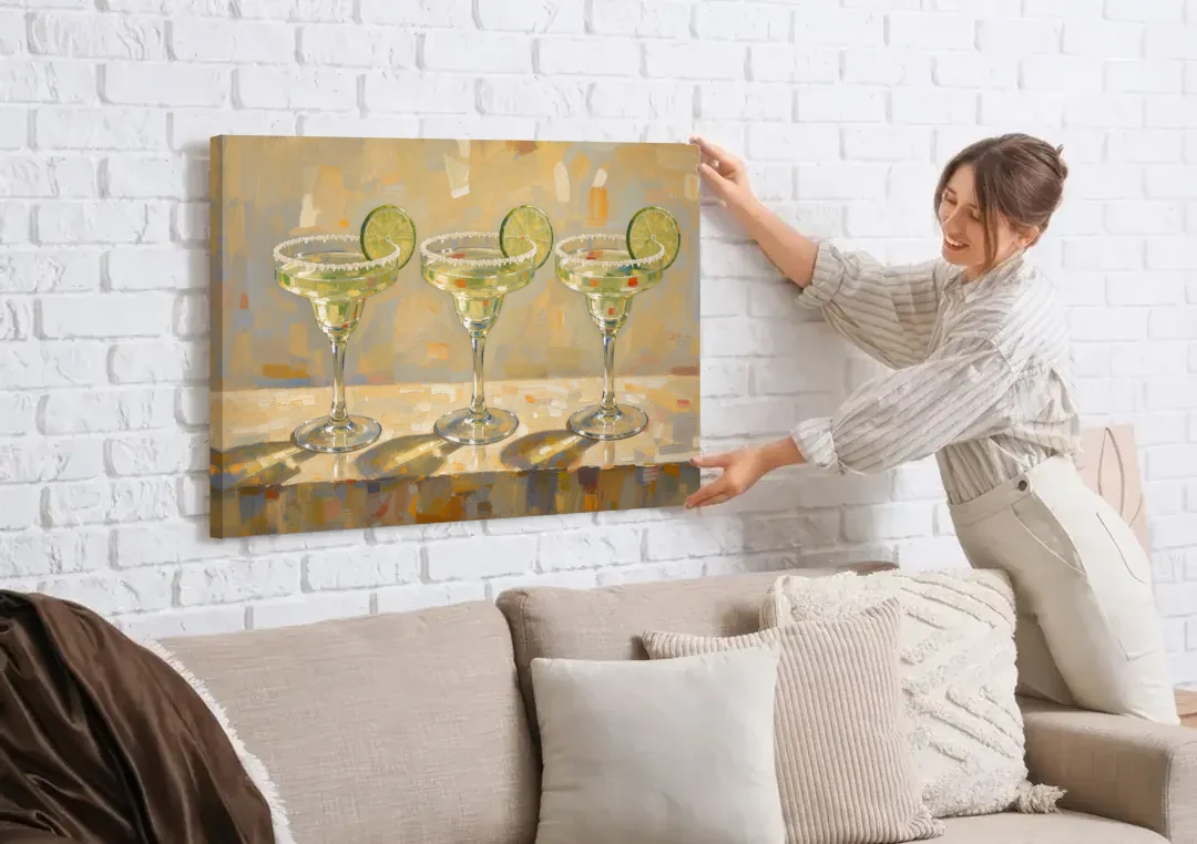 Margarita Painting Trio with Lime Wheels canvas wall art being hung on a white brick wall above a sofa