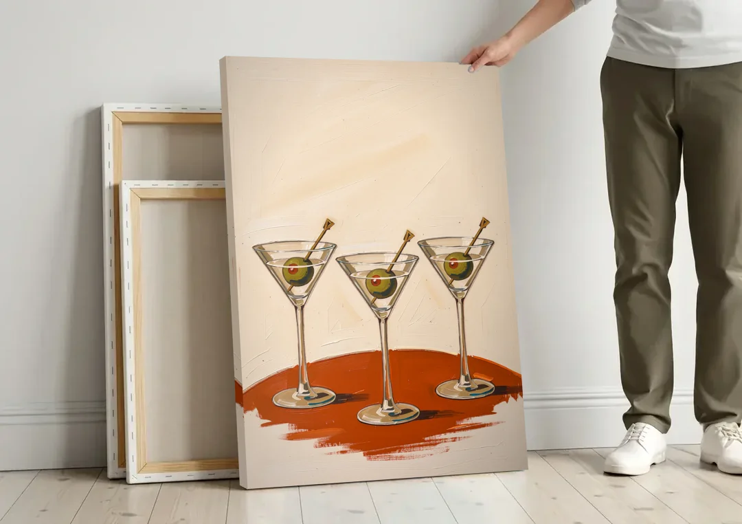 Martini Wall Art Trio with Green Olives canvas wall art leaning against a wall next to blank canvases