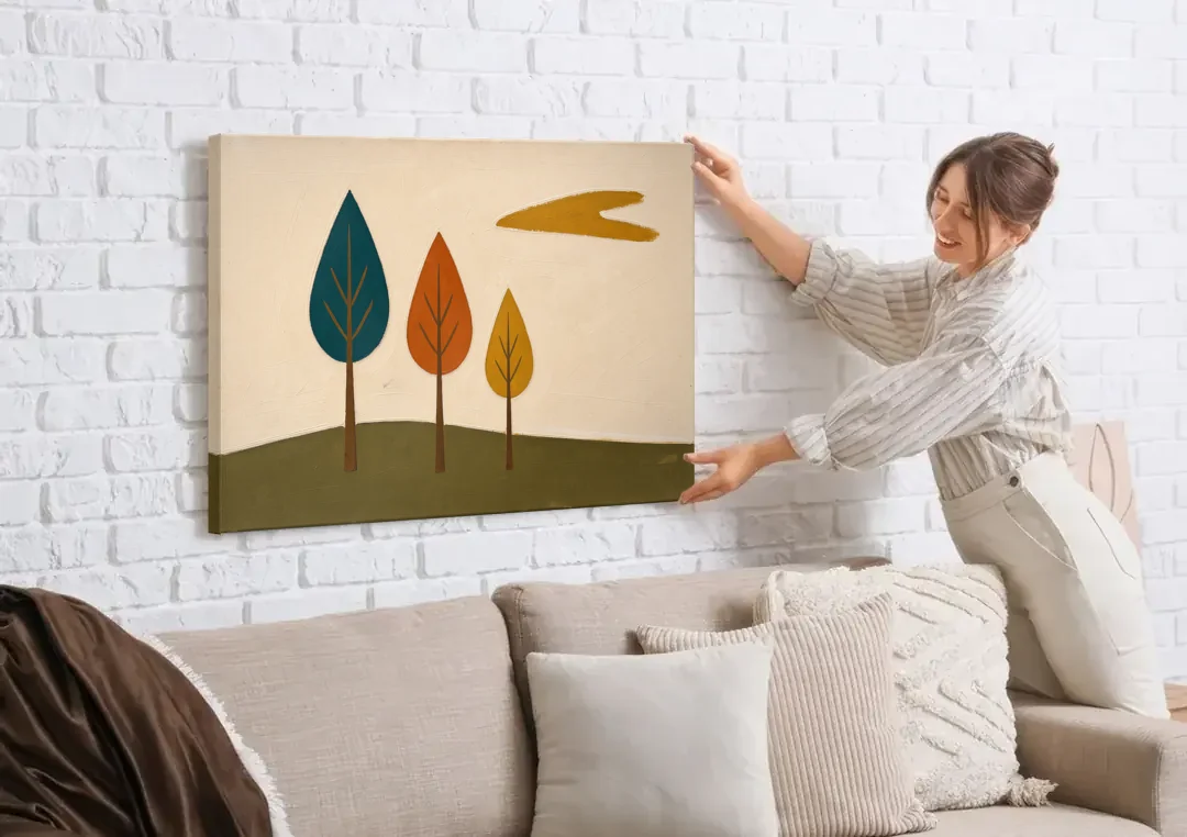 Mid Century Modern Wall Art of Three Trees canvas wall art being hung on a white brick wall above a sofa