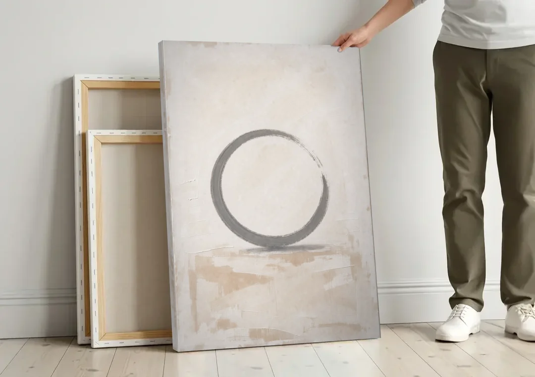 Minimal Wall Art of an Open Graphite Circle canvas wall art leaning against a wall next to blank canvases