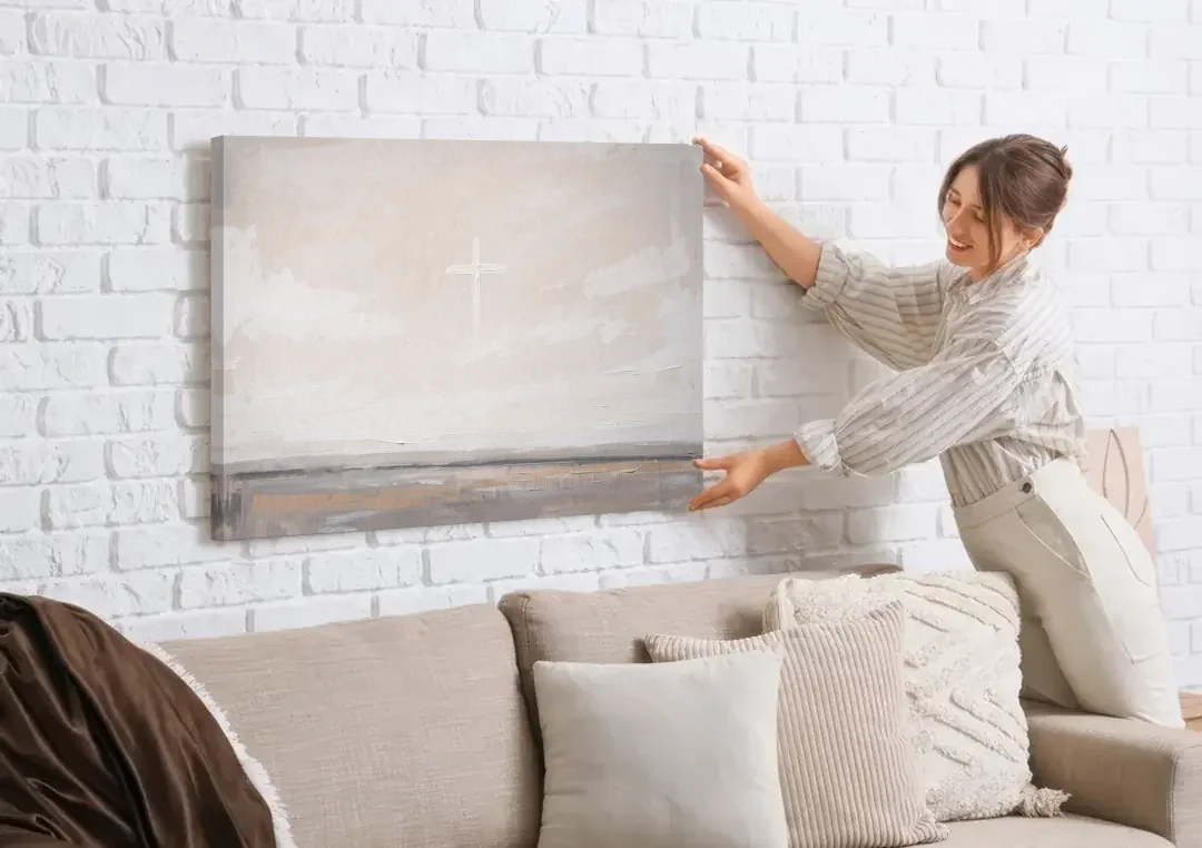 Minimalist Christian Wall Art with a Misty Cross canvas wall art being hung on a white brick wall above a sofa