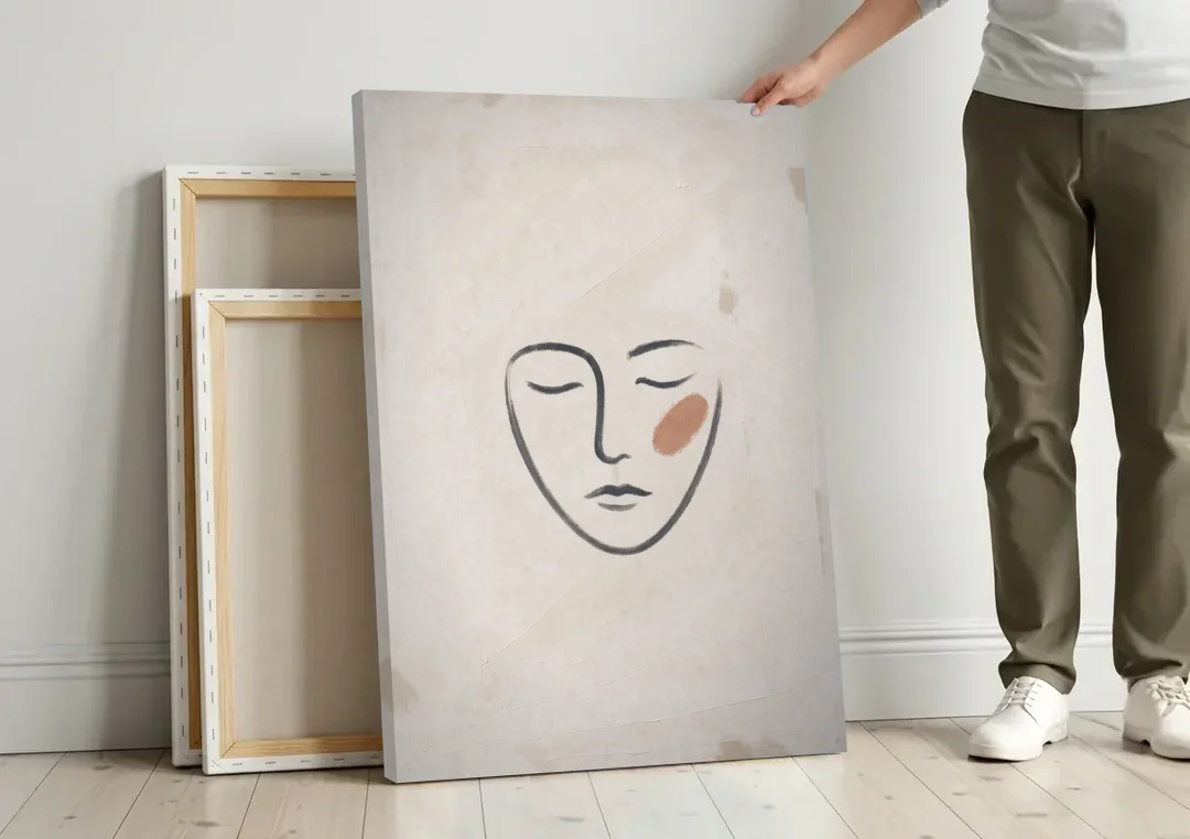 Minimalist Line Art Face with Terracotta Blush canvas wall art leaning against a wall next to blank canvases