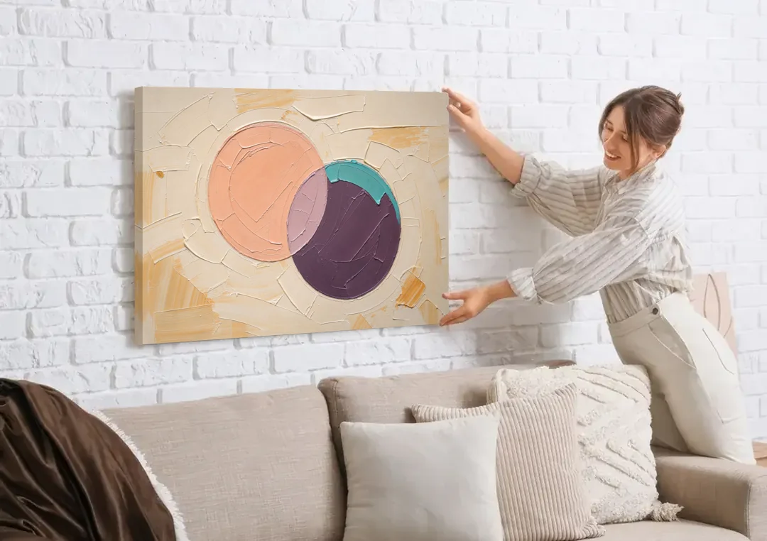 Modern Abstract Overlapping Peach and Plum Discs canvas wall art being hung on a white brick wall above a sofa