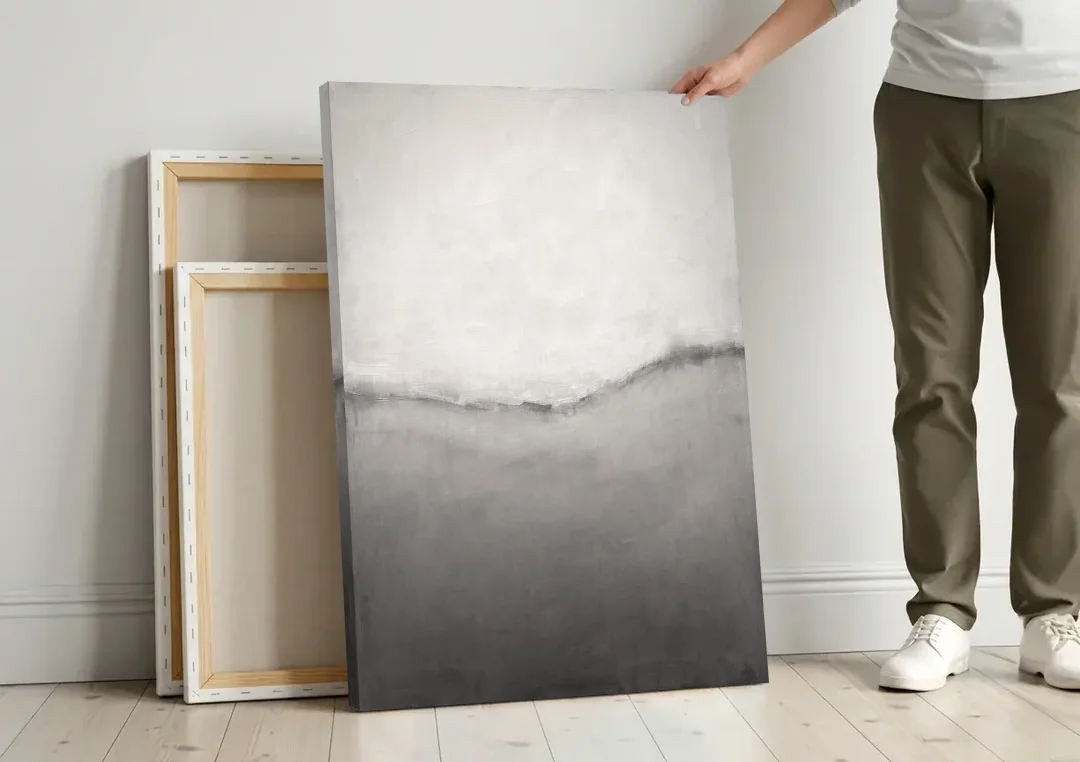 Modern Black and White Abstract Feathered Grey Seam canvas wall art leaning against a wall next to blank canvases