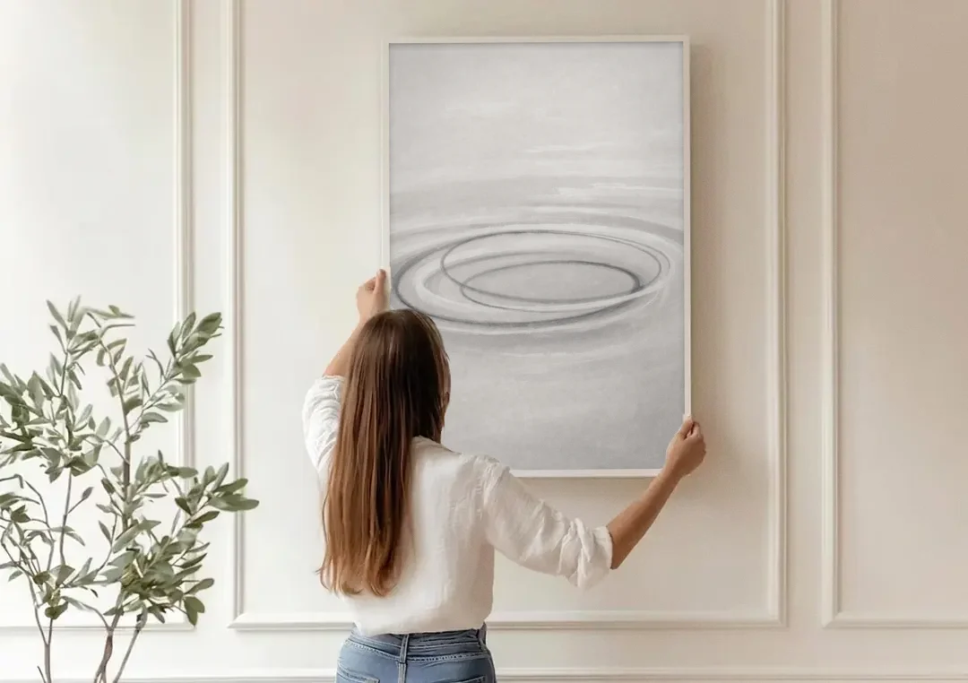 Modern Black White and Grey Abstract Ripple Rings canvas wall art being hung on a paneled wall