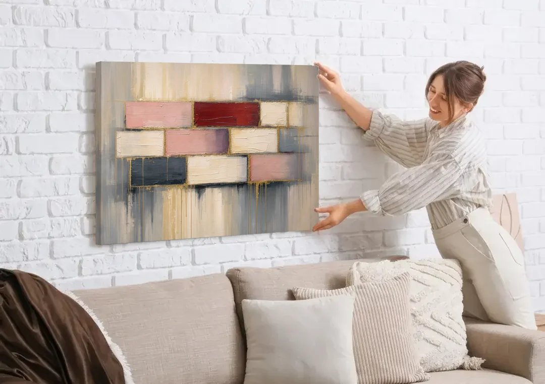 Modern Textured Wall Art of Blush and Crimson Stones canvas wall art being hung on a white brick wall above a sofa