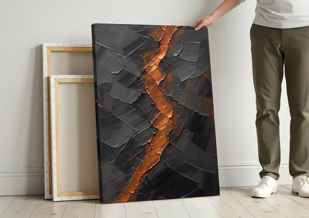 Molten Copper Fissure in Black and Copper canvas wall art leaning against a wall next to blank canvases
