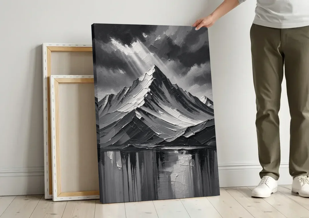 Moody Mountain Painting Under Breaking Light canvas wall art leaning against a wall next to blank canvases