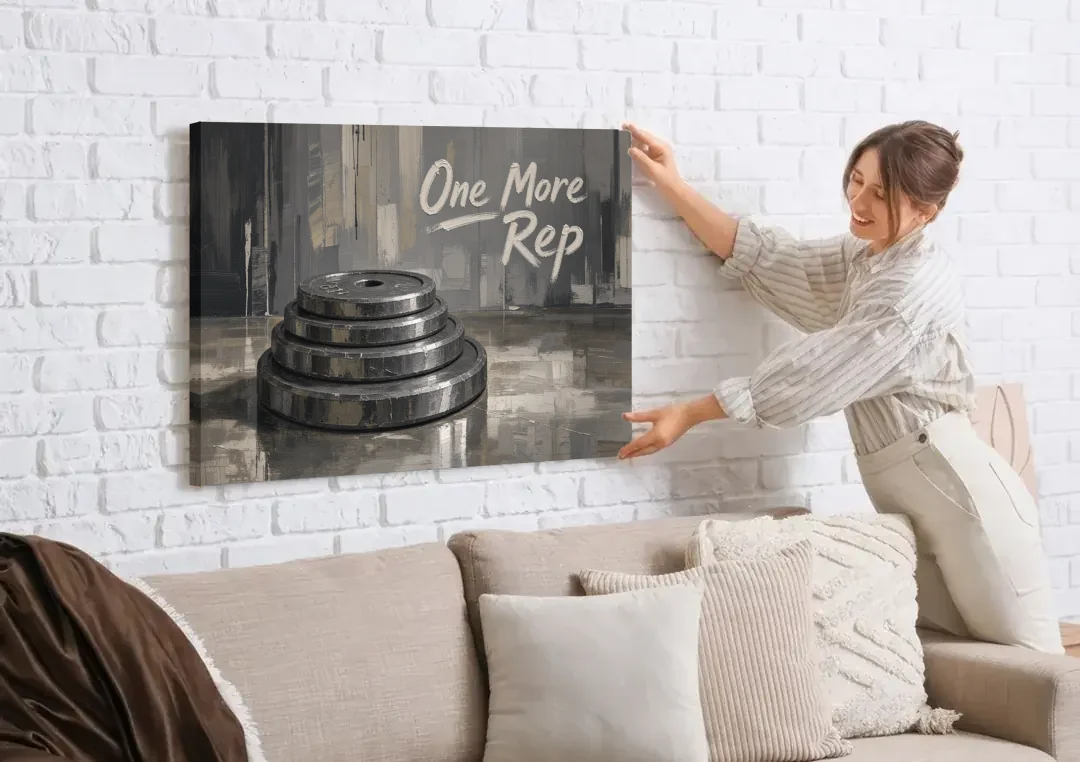 Motivational Quote Canvas One More Rep Weight Stack canvas wall art being hung on a white brick wall above a sofa