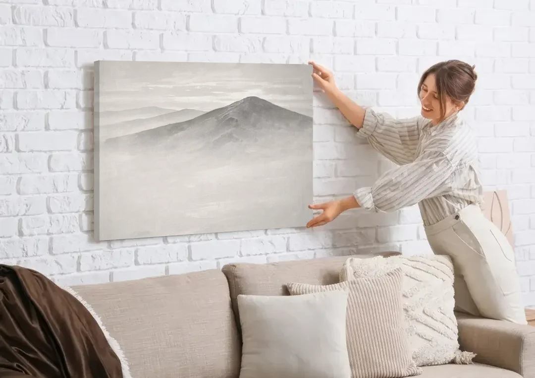 Mountain Ridge Above a Sea of Mist canvas wall art being hung on a white brick wall above a sofa