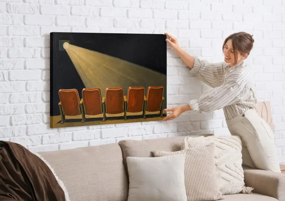 Movie Theater Wall Art with Five Red Seats canvas wall art being hung on a white brick wall above a sofa