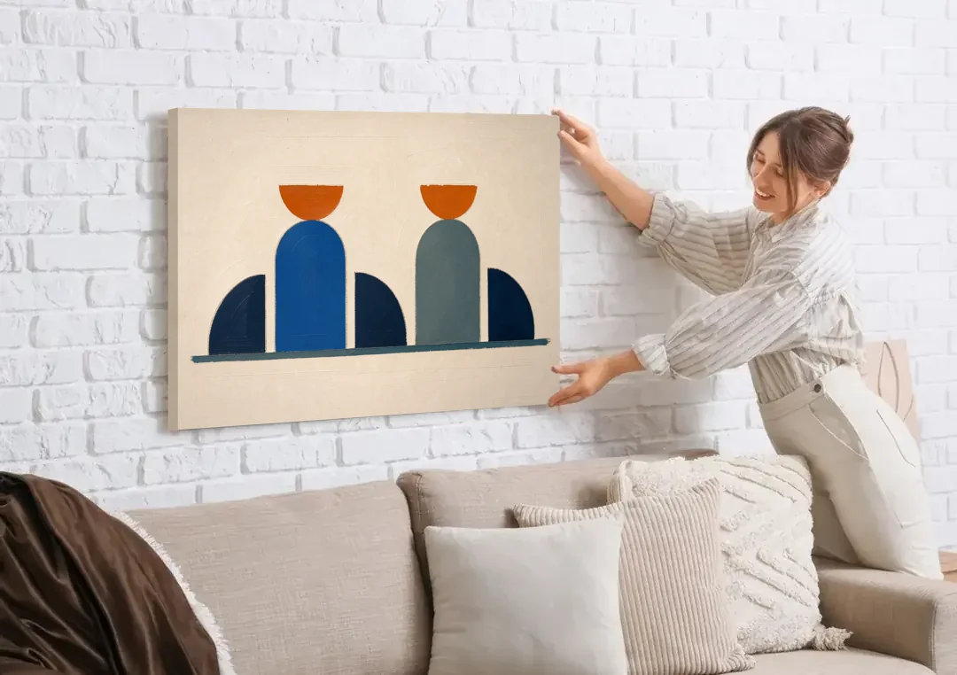 Navy Blue Wall Decor with Two Orange Suns canvas wall art being hung on a white brick wall above a sofa