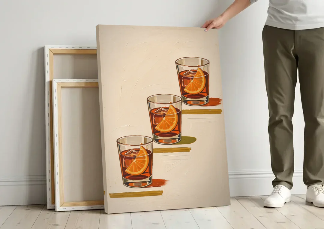 Negroni Wall Art with Three Orange Slices canvas wall art leaning against a wall next to blank canvases