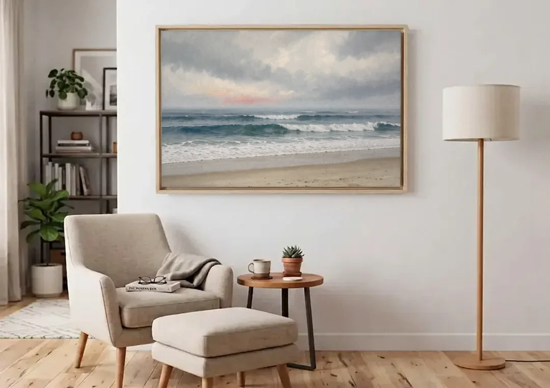 Neutral Coastal Pink Glow Over Gray Surf canvas wall art above an armchair in a bright living room