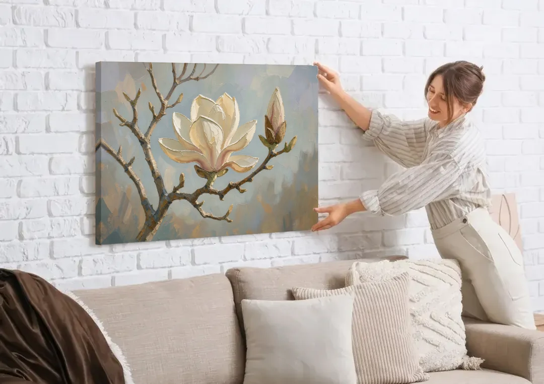 Neutral Flower Painting of a Cream Magnolia Branch canvas wall art being hung on a white brick wall above a sofa