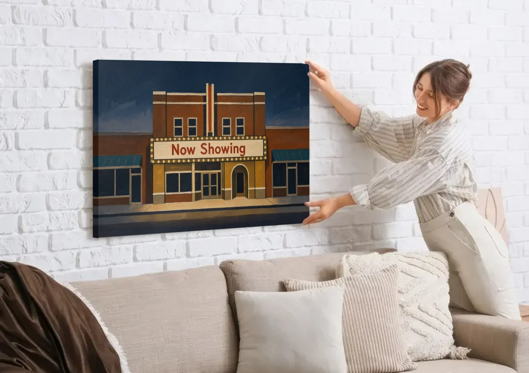 Now Showing Small Town Movie Theater at Dusk canvas wall art being hung on a white brick wall above a sofa