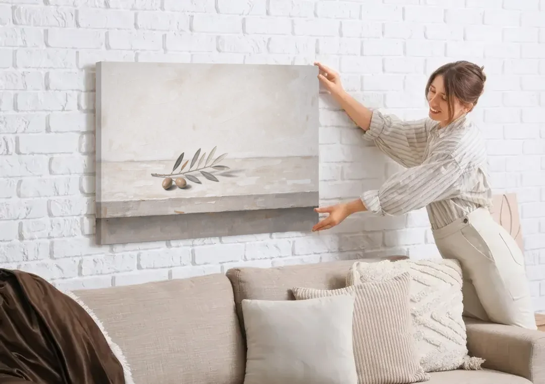 Olive Sprig on a Whitewashed Plaster Ledge canvas wall art being hung on a white brick wall above a sofa