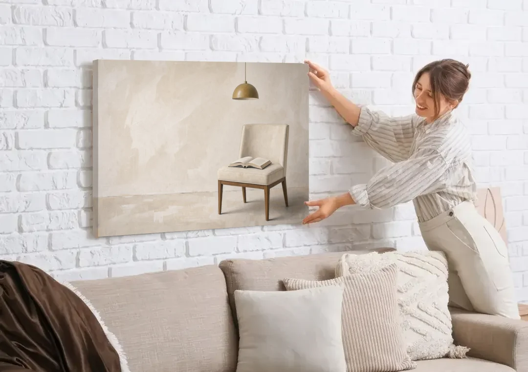 Open Book Painting on a Cream Side Chair canvas wall art being hung on a white brick wall above a sofa