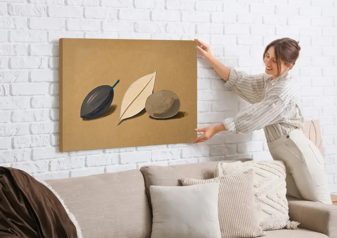 Organic Modern Home Decor with Seed, Leaf and Pebble canvas wall art being hung on a white brick wall above a sofa