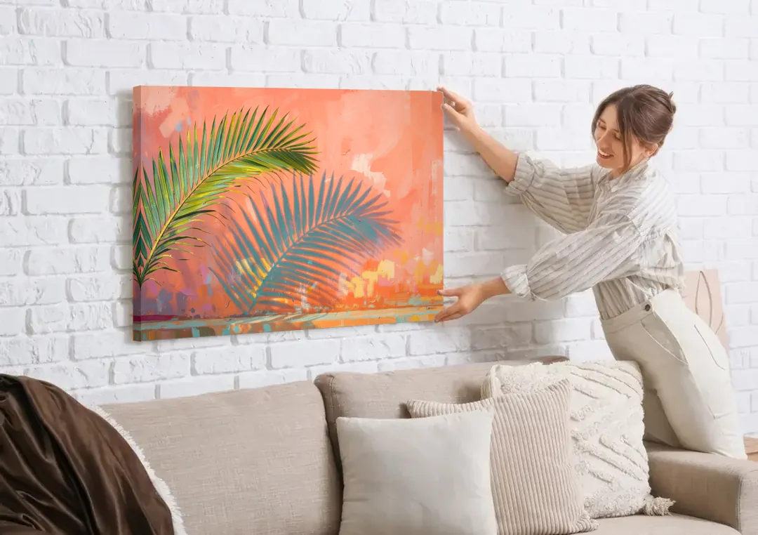 Palm Frond Wall Art with Coral Stucco Shadow canvas wall art being hung on a white brick wall above a sofa