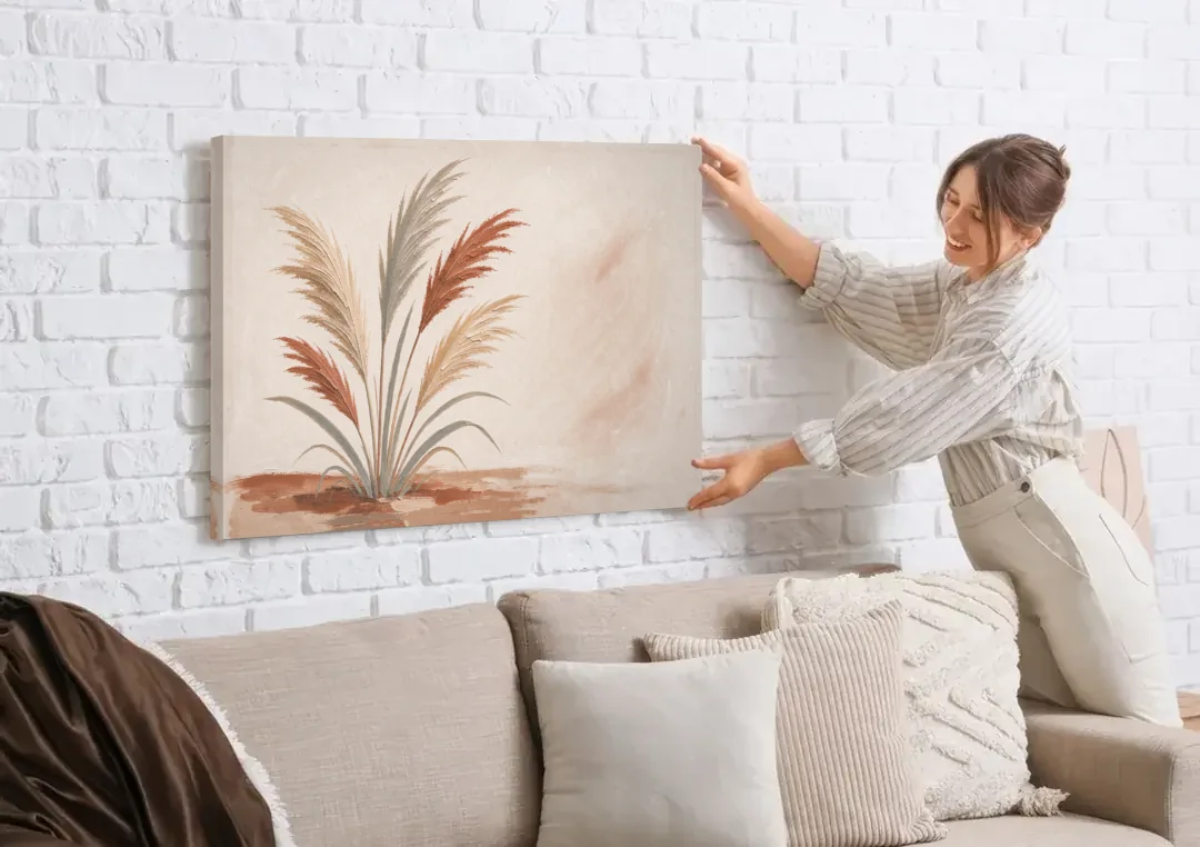 Pampas Grass Painting in a Soft Breeze canvas wall art being hung on a white brick wall above a sofa