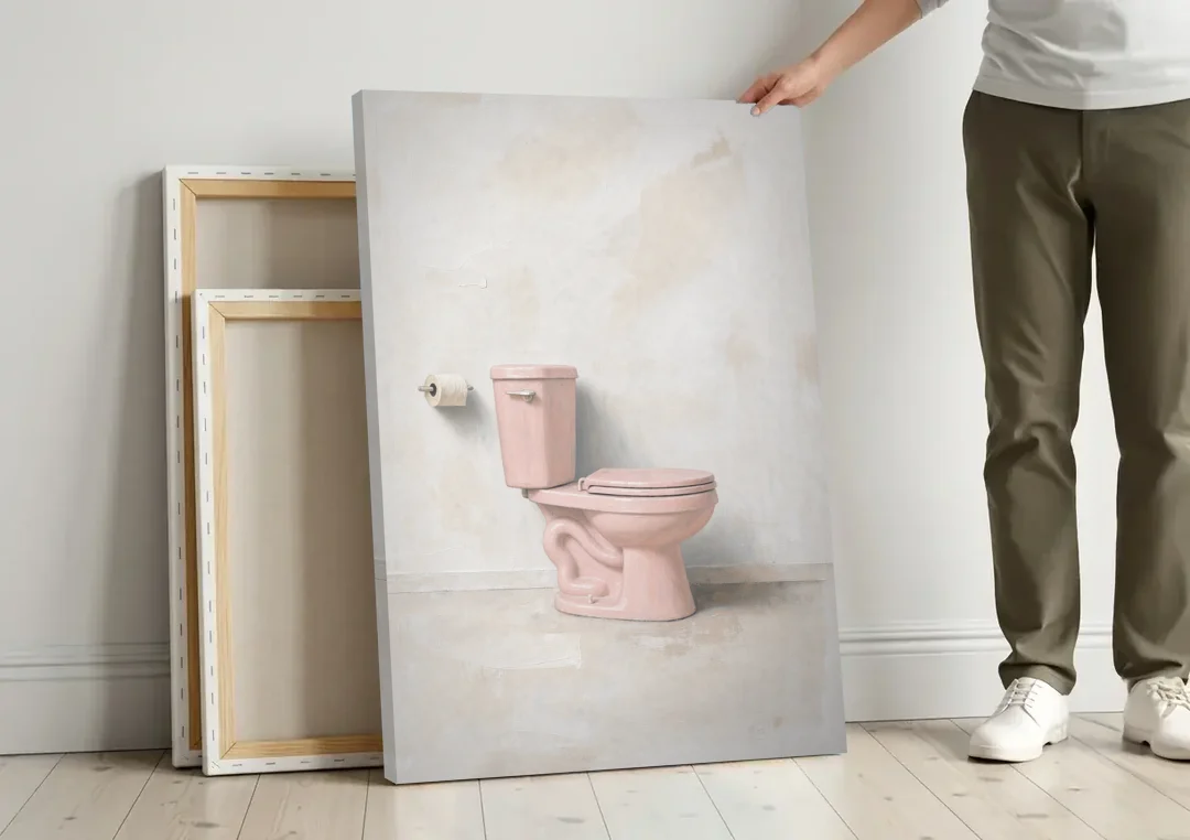 Pastel Bathroom Decor with a Pink Toilet in Profile canvas wall art leaning against a wall next to blank canvases