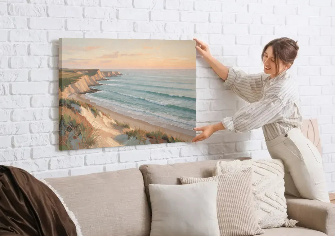Peach Dawn Seascape Over Chalk Bluffs canvas wall art being hung on a white brick wall above a sofa