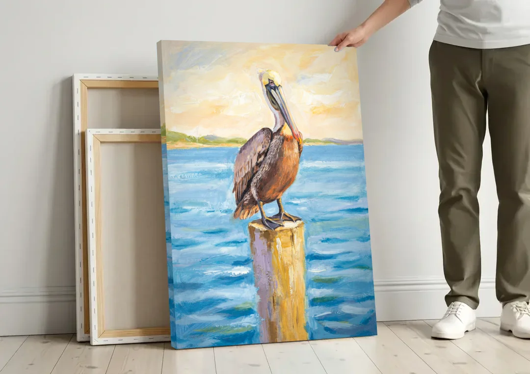 Pelican Painting on the Morning Piling canvas wall art leaning against a wall next to blank canvases
