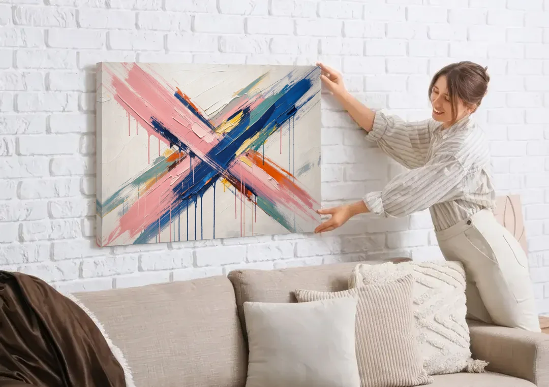 Pink and Blue Abstract Painting Crossed in Cobalt canvas wall art being hung on a white brick wall above a sofa