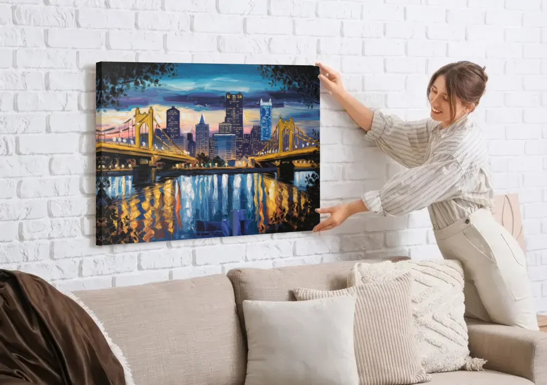 Pittsburgh Downtown Lights at Night canvas wall art being hung on a white brick wall above a sofa