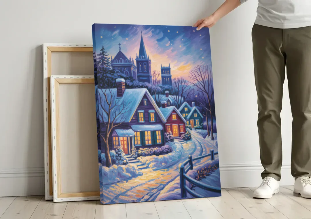 Quebec Snowy Village Scene canvas wall art leaning against a wall next to blank canvases