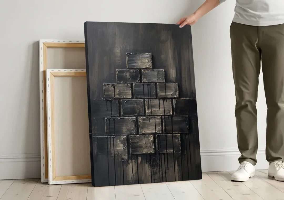 Relief Wall Art of Stacked Charcoal Blocks canvas wall art leaning against a wall next to blank canvases