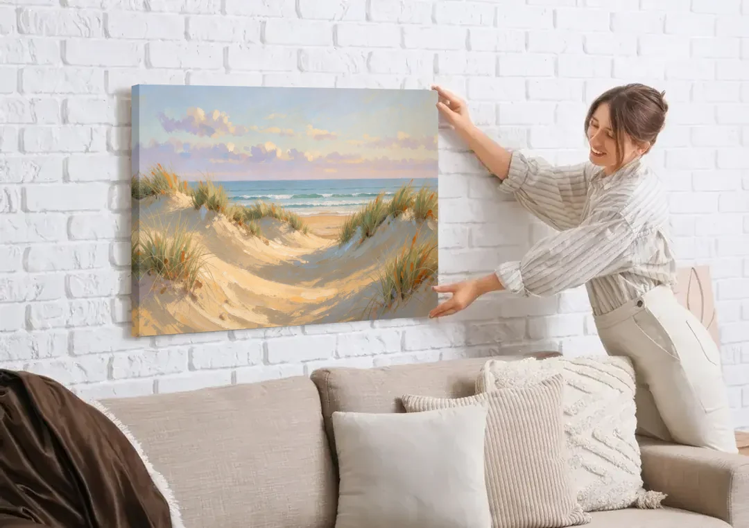 Sand Dunes and Beach Grass Under Lavender Clouds canvas wall art being hung on a white brick wall above a sofa