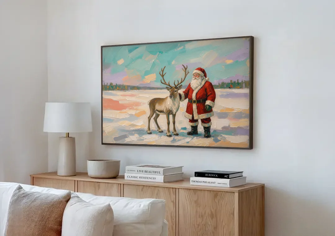 Santa and Reindeer Painting on the Open Snow canvas wall art above a wooden sideboard next to a sofa