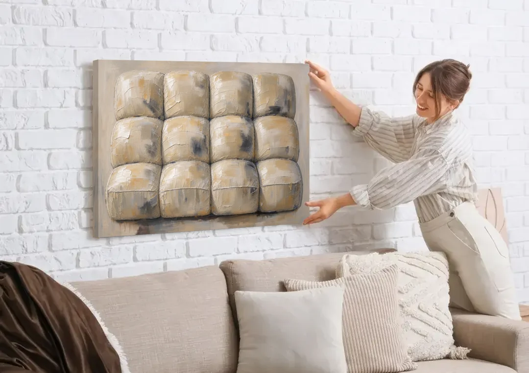 Sculptural Wall Art of Tufted Cream Pillows canvas wall art being hung on a white brick wall above a sofa