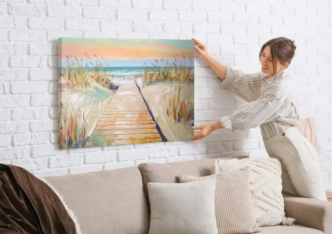 Seaside Boardwalk Dreams canvas wall art being hung on a white brick wall above a sofa