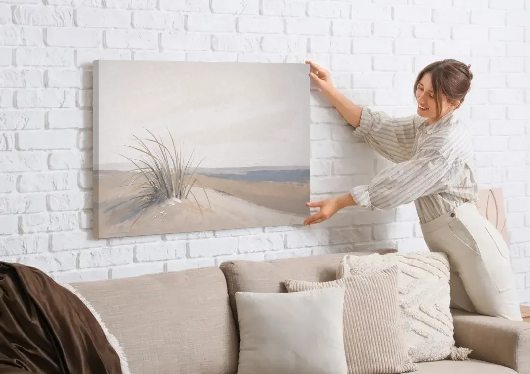 Set of 2 Wall Art with Windblown Dune Grass canvas wall art being hung on a white brick wall above a sofa