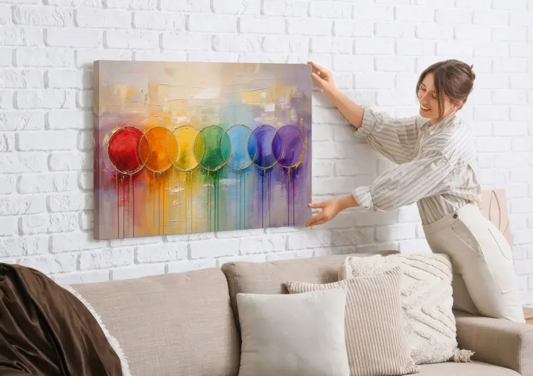 Seven Overlapping Chakra Circles with Gold Drips canvas wall art being hung on a white brick wall above a sofa