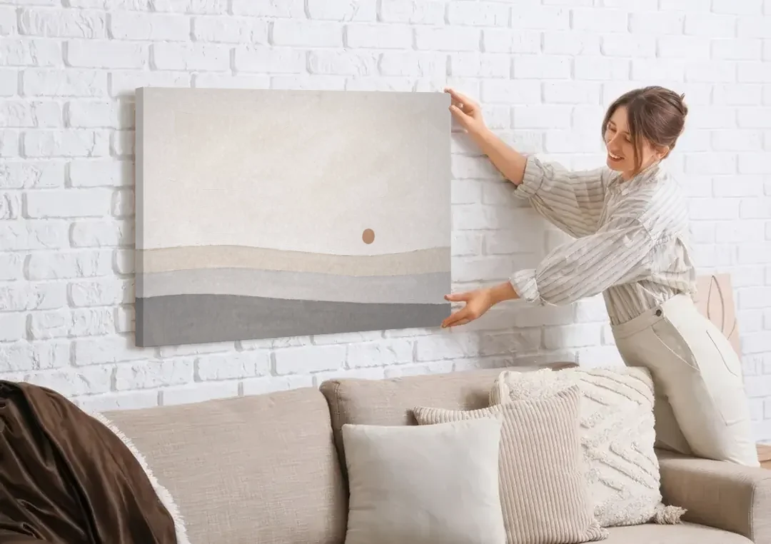Small Sun Above Three Bands of Rolling Hills canvas wall art being hung on a white brick wall above a sofa