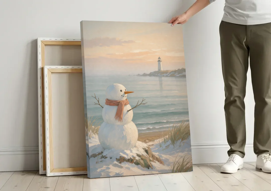Snowman Watching the Coastal Lighthouse canvas wall art leaning against a wall next to blank canvases