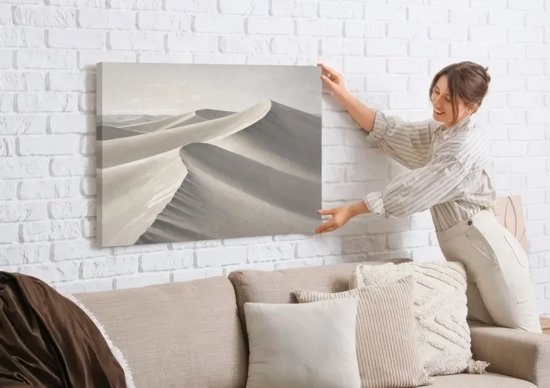 Sophisticated Dune Crests in Ivory and Charcoal canvas wall art being hung on a white brick wall above a sofa