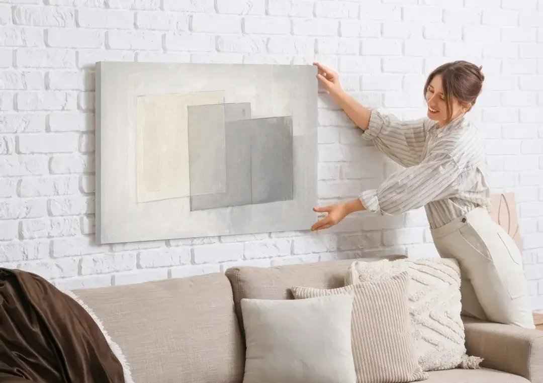 Neutral Abstract Stacked Tissue Panels canvas wall art being hung on a white brick wall above a sofa