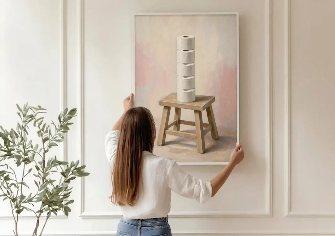Stacked Toilet Paper Rolls on a Wooden Stool canvas wall art being hung on a paneled wall