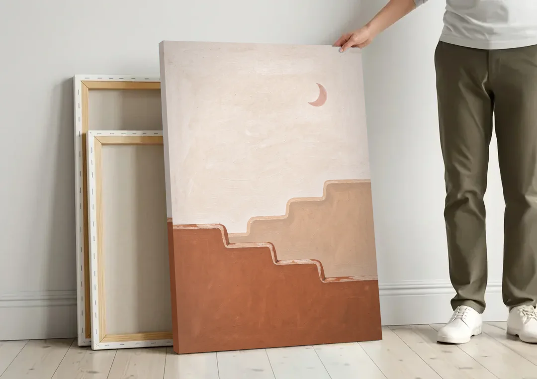 Stepped Adobe Wall Under a Crescent Moon canvas wall art leaning against a wall next to blank canvases