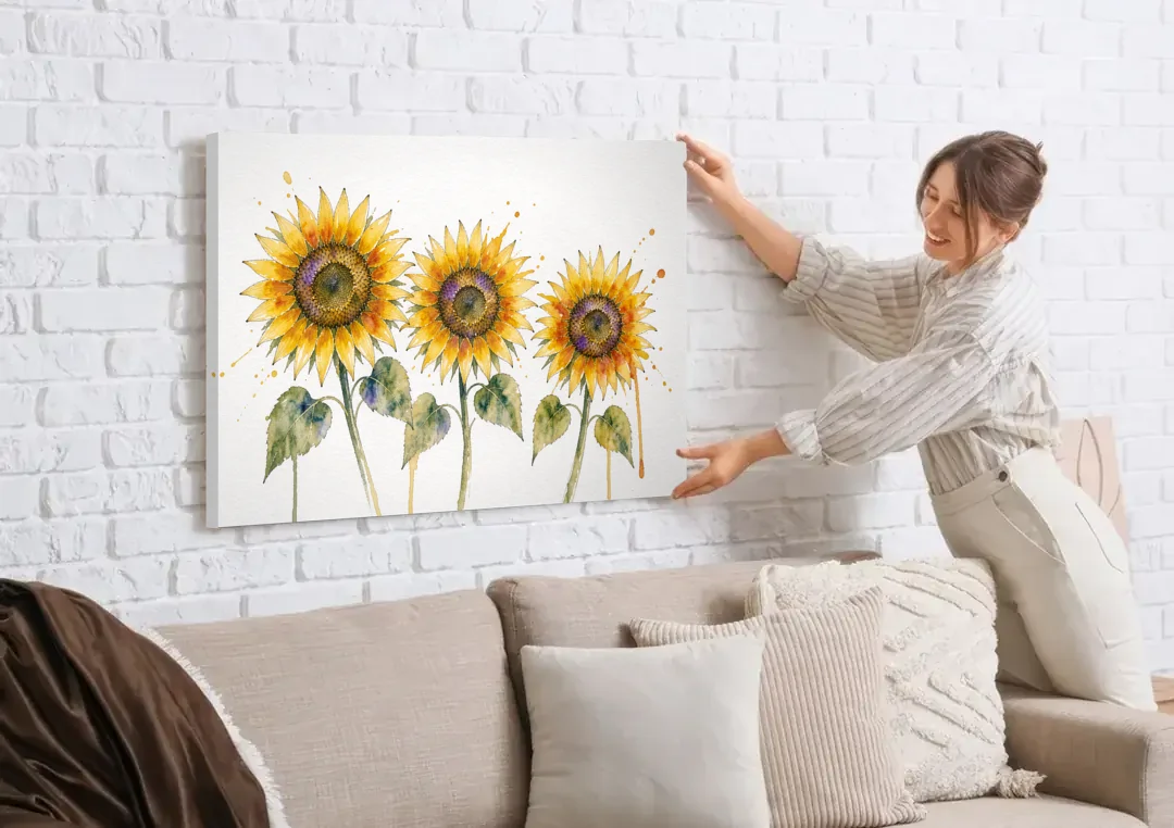 Sunflower Watercolor Painting with Amber Splashes canvas wall art being hung on a white brick wall above a sofa